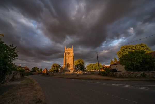Wayne Munton - Swarby Church near Sleaford	
Swarby Church near Sleaford.  Taken just before sunset after storm clouds rolled overhead.
The perfect view of the centre of a Lincolnshire village in beautiful light almost stalled in time.
I often look at this view when driving through the village knowing that when the light is right it’s going to make a beautiful picture.
Luckily I was there when the low sun hit it as shown in the picture.